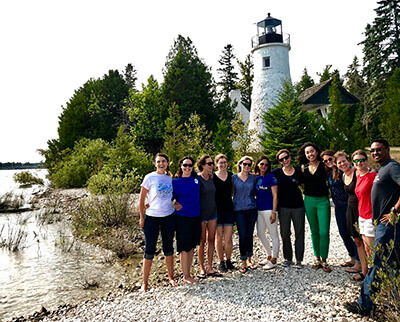 a group of people pose for a photo in front of a lighthouse