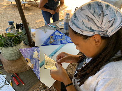 a woman peals stickers off a sheet to place on her diarama
