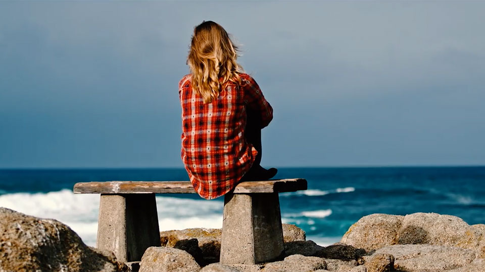 Emily Aiken sitting on a bench looking at the ocean